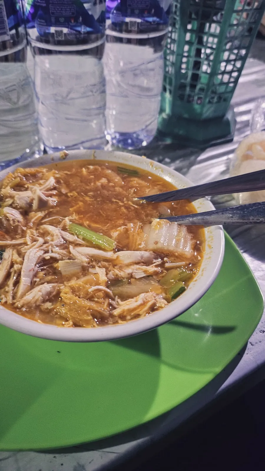Semangkuk sup ayam dengan sayuran di atas nampan hijau.